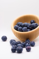 Ripe juicy beautiful blueberries in wooden bowl isolated on white background. Vertical with copy space above