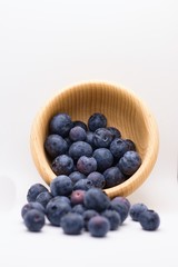 Overturned wooden bowl of fresh blueberries isolated on white background