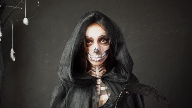 Creepy female in Halloween scary Death Reaper cape costume heavy professional spooky Skeleton makeup approaching camera