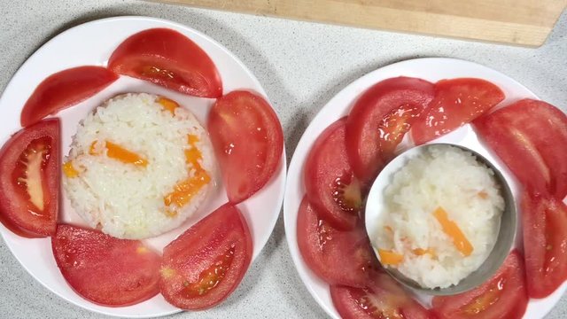 Rice with vegetables with tomato, cauliflower. Closeup indian vegeterians food girl hand puts rice in a bowl tomatoes, dish kitchen, appetisers of cuisine, rice, tomatos.  Cooked rice steaming.