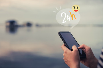 Woman hand using smartphone to do work 24 hour icons and smile face. Business communication  technology concept.