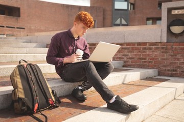 College student using laptop on stairs
