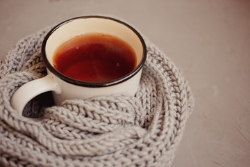 warm scarf, cup of tea on gray background, top view, with copy space