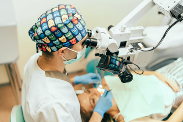 Dentist examine oral cavity of female patient with microscope, up view.