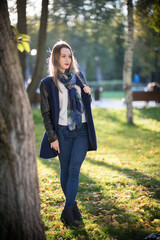 Beautiful girl with red lipstick standing in the park.