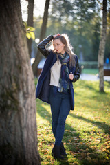 Beautiful girl with red lipstick standing in the park runs fingers through the hair. Autumn