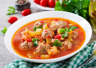 Hot stew tomato soup with meatballs and vegetables closeup in a bowl on the table. Albondigas soup,...