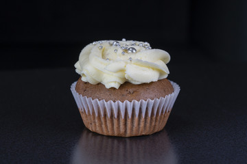 Fragrant, vanilla capcake with berry filling and honey cream cheese on black background