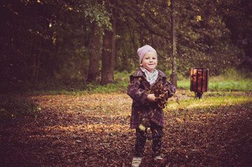 Little girl throws up colorful autumn leaves