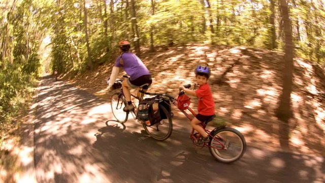 Cinemagraph of a mother and son biking on a bike trail in the forest.