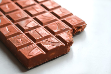 Chocolate bar with broken corner on white table