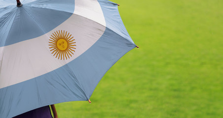 Argentina flag umbrella. Close up of printed umbrella over green grass lawn / field. Rainy weather...