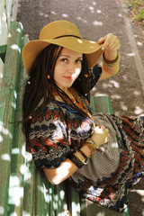 Pretty woman with dreadlocks dressed in boho style dress and hat