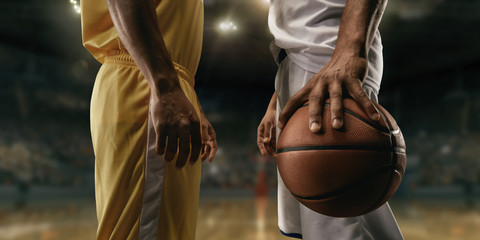 Two black basketball players on big professional arena before the game. Two teams. Players collided face to face. Player holds a ball. Close up