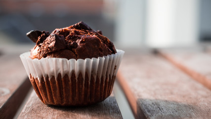 Chocolate muffin for morning breakfast on a wooden table at sunrise