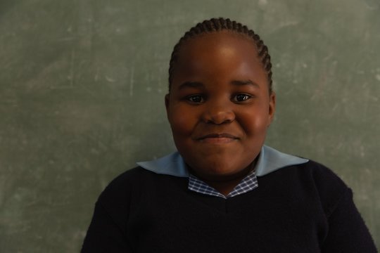 Schoolgirl standing near chalkboard in classroom