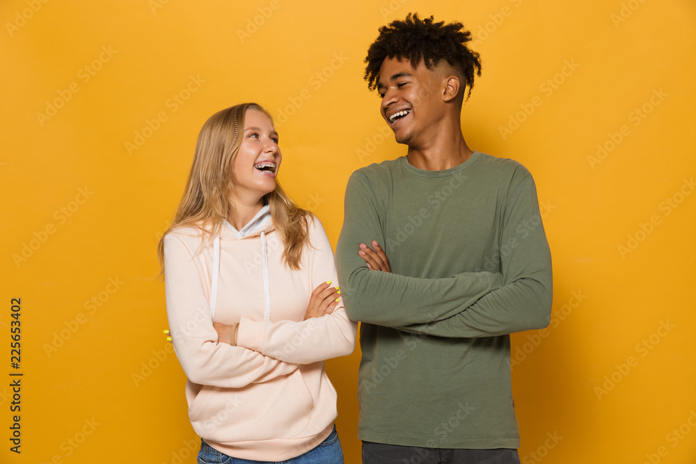 Wall mural Photo of multiethnic students man and woman 16-18 with dental braces laughing, isolated over yellow background - Wall murals