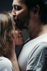 Close-up. A young man gently kisses a woman.  His hands hold her head.
