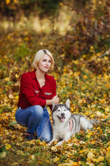 Naklejka na ściany i meble Beautiful caucasian girl plays with husky dog in autumn forest