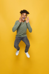 Full length photo of satisfied african guy having stylish afro hairdo screaming or calling, isolated over yellow background