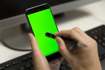 Women's hands touches phone screen with pen for touchscreen. Mobile phone with a green screen.
