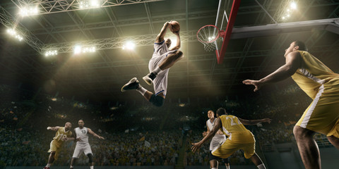Basketball players on big professional arena during the game. Basketball player makes slum dunk