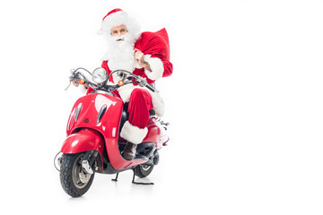 confident santa claus in costume holding christmas sack and riding on scooter isolated on white background