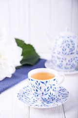 Porcelain cup of green tea and white hydrangea on a light wooden background. Free space