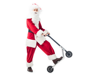 smiling santa claus in costume standing with kick scooter isolated on white background