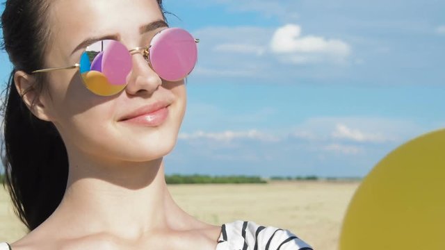 Girl with balloons in sunglasses. Balloons are reflected in sunglasses.