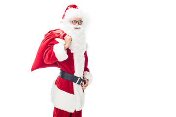 cheerful santa claus in eyeglasses holding christmas sack over shoulder isolated on white background