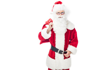 happy santa claus in eyeglasses holding christmas sack over shoulder isolated on white background