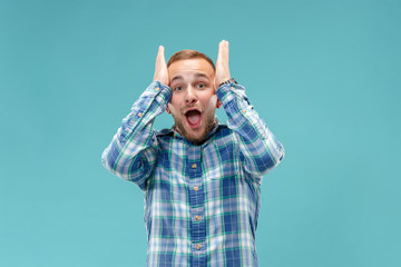 Fototapeta premium Wow. Attractive male half-length front portrait on blue studio backgroud. Young emotional surprised bearded man standing with open mouth. Human emotions, facial expression concept. Trendy colors