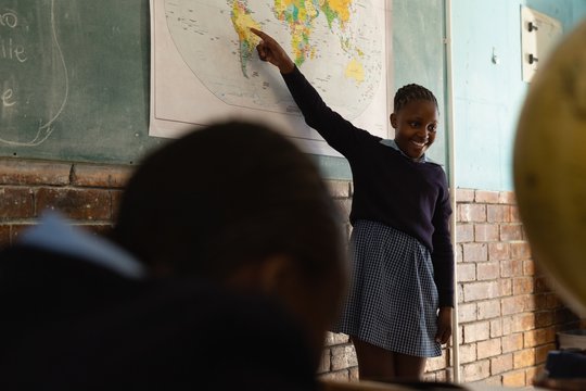 Schoolgirl explaining about world map in classroom