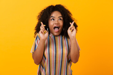 Excited young african cute girl posing isolated over yellow background make hopeful gesture.