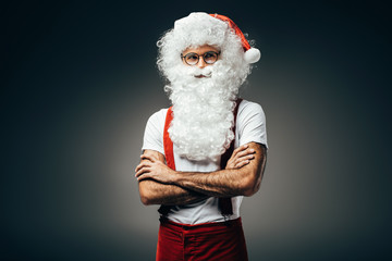 santa claus in eyeglasses standing with crossed arms isolated on grey background