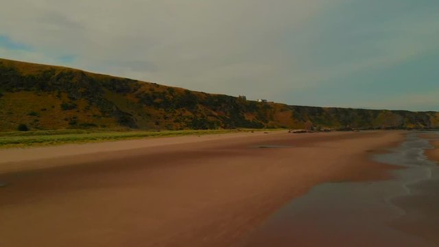 Beautiful views from drone of a long wide beach during low tide under a blue cloudy sky with some views of a family walking along.