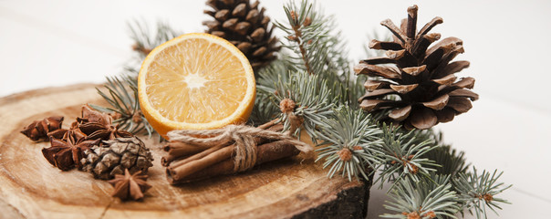 Pinecones and spices on wooden background.
