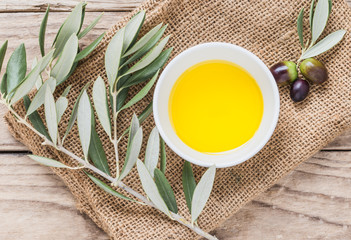 Olive oil bowl on rustic wooden background.