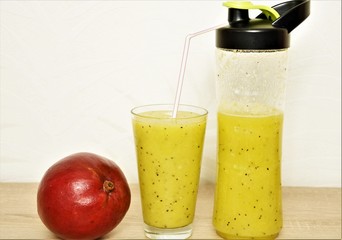 fruit and berry smoothies in a bottle and glass and red mango in the peel