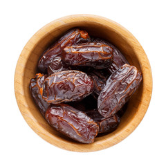 Dried dates in wooden bowl isolated on white. Top view