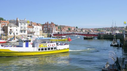 Pleasure boats leaving, and arriving, in Whitby harbour, on a summer evning.