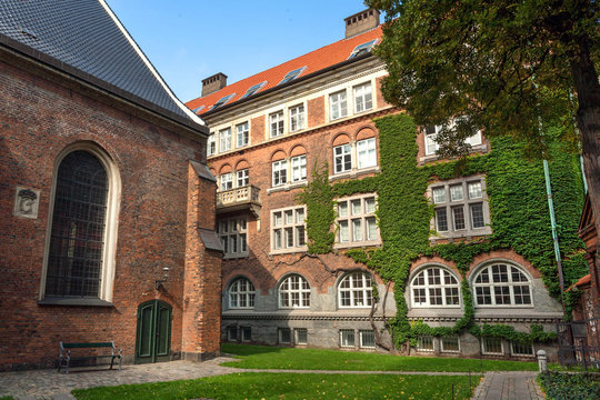 Colorful courtyard of 15th century Sankt Peders church with brick walls in Copenhagen, Denmark. Facade of historical building with green plants around