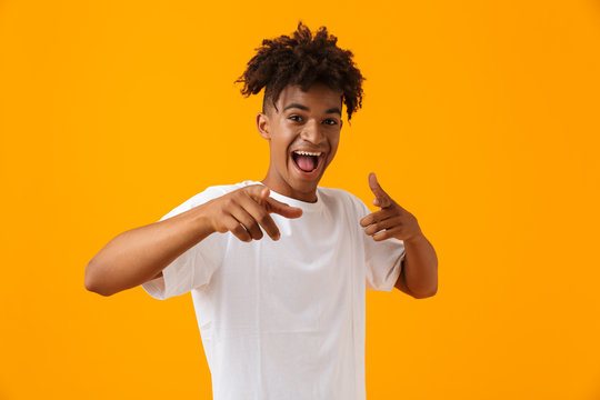 Happy young african man posing isolated over yellow background pointing.