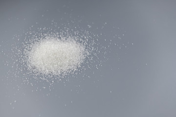 Pile of sugar on gray background.