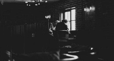 silhouette of two men talking during a business meeting near a window in black and white