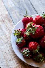 photo strawberry with stems in a plate on a wooden table