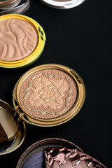 Set of bronze powder with makeup brushes on black background