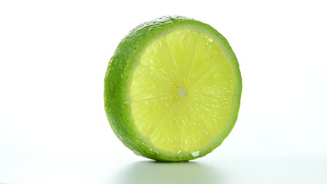 Fresh green lime slice is slowly rotating in the studio
