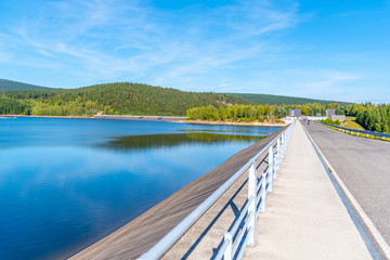 Josefuv Dul Dam, Earth-filled dam in Jizera Mountains with asphalt road on the top, Czech Republic. Sunny summer day.